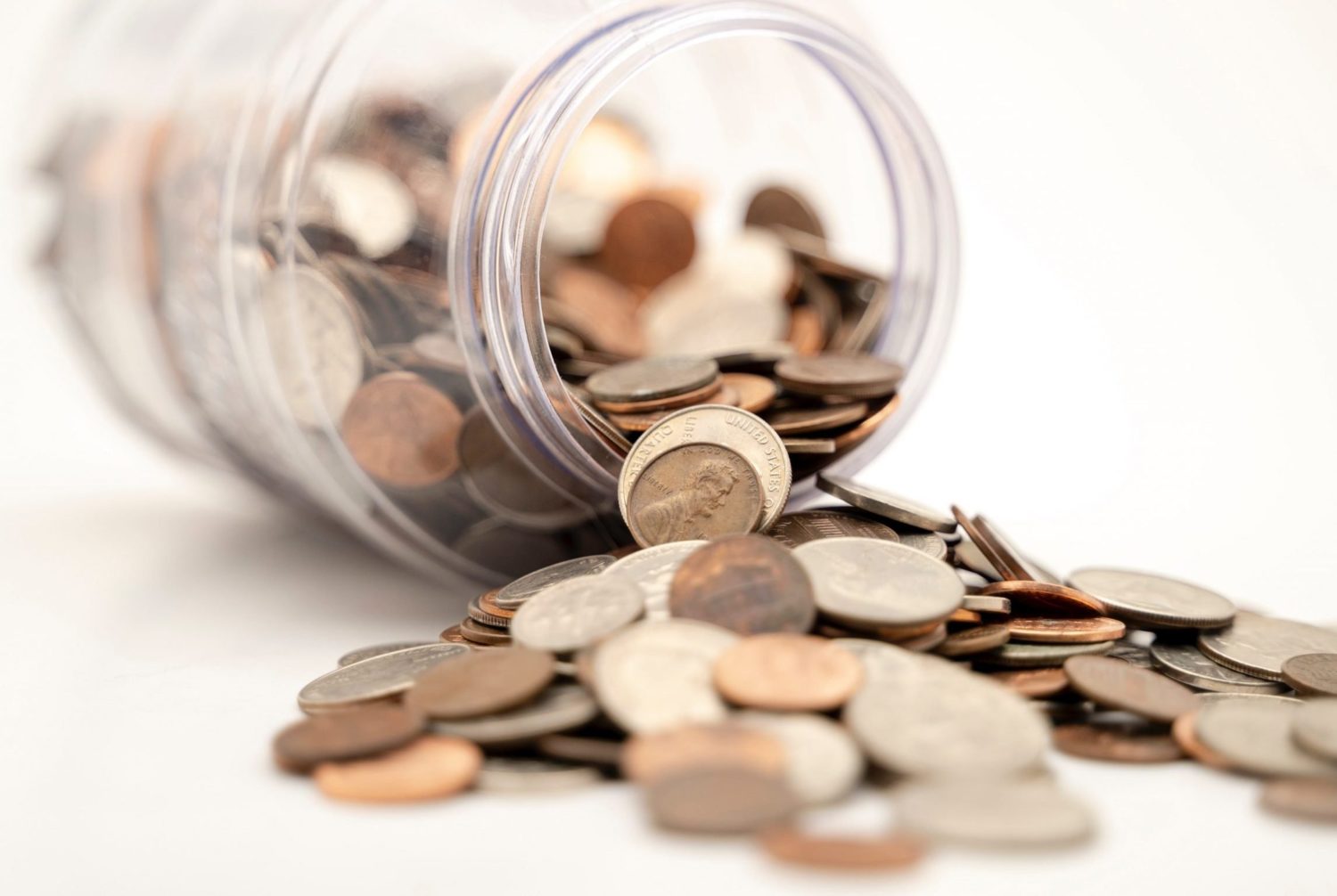 glass jar with coins spilling from it